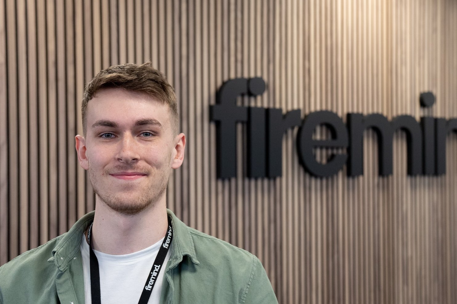 Harry Barden - Firemind Developer sitting in front of Firemind signage