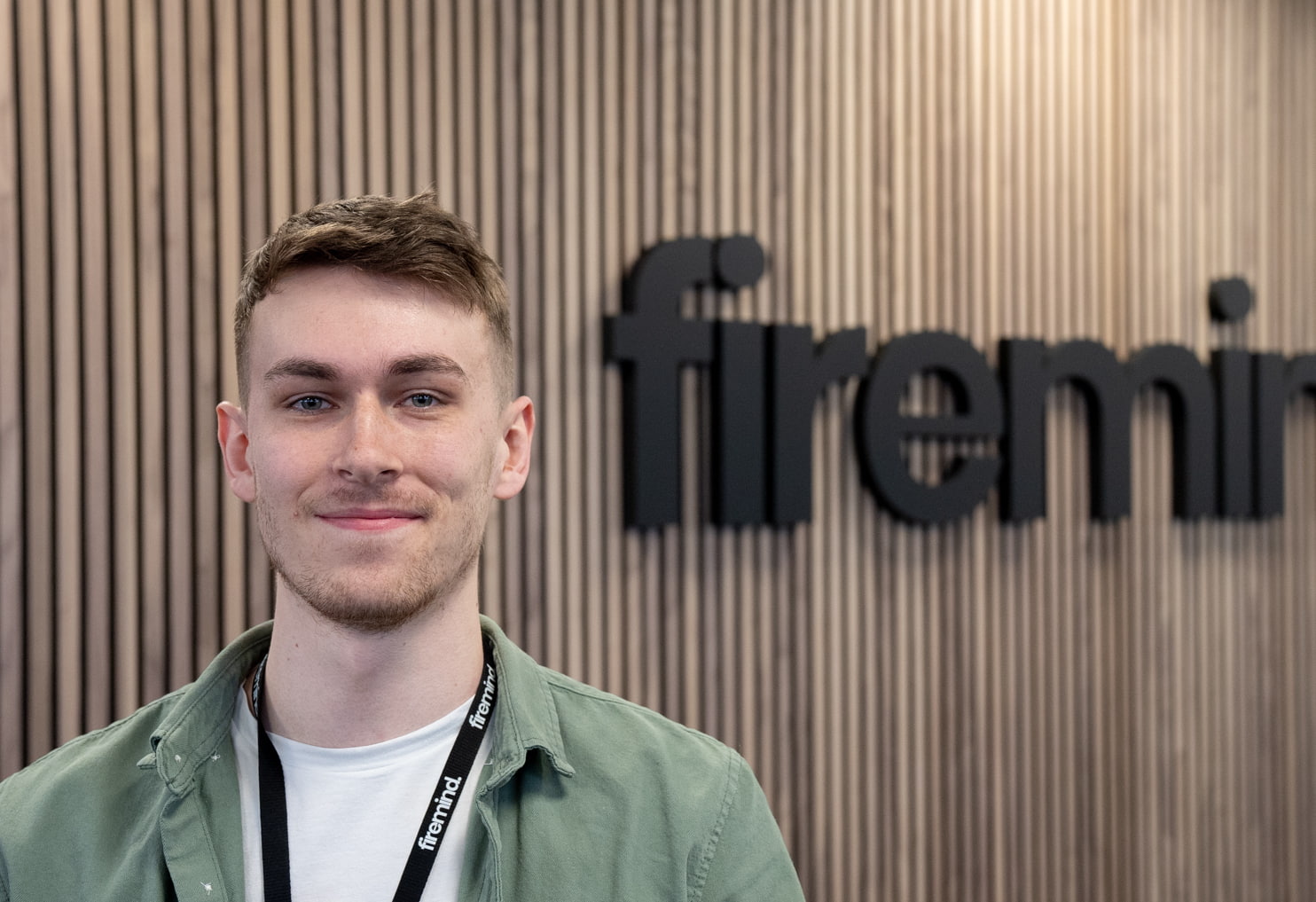 Harry Barden - Firemind Developer sitting in front of Firemind signage