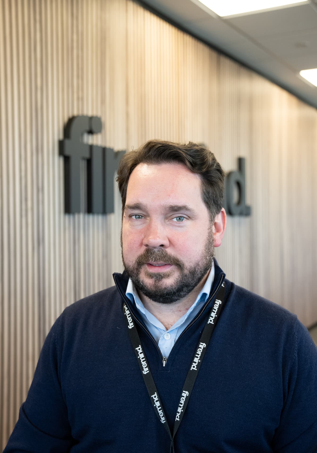 An image of a Firemind Solution Architect in front of Firemind signage